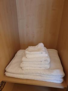 una pila de toallas blancas sentadas en un estante en London Luxury Apartments 3 Bedroom Sleeps 8 with 3 Bathrooms 5 mins Walk to tube station free parking en Ilford