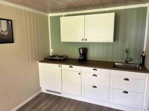 a kitchen with white cabinets and a sink at Dalsøren Camping og hytter in Luster