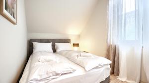 sypialnia z łóżkiem z białą pościelą i oknem w obiekcie Apartamenty Sun & Snow Rumiankowa w Rewalu