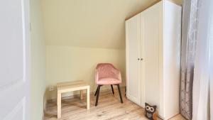 a pink chair and a table in a room at Apartamenty Sun & Snow Rumiankowa in Rewal