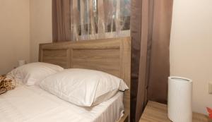 1 cama con cabecero de madera y almohadas blancas en Melissa Luxury Apartments, en Agios Leon