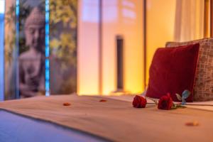 a bed with two roses and a red pillow at Le Baiser de Shogun in Ensival