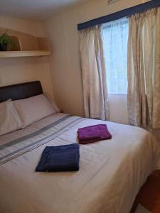 Dos toallas en una cama en un dormitorio con ventana. en Cosy Caravan at Blackmoor Farm, en Ludchurch