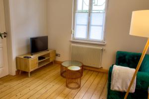 sala de estar con TV, sofá y mesa en La Maison Forestière, en Niederbronn-les-Bains
