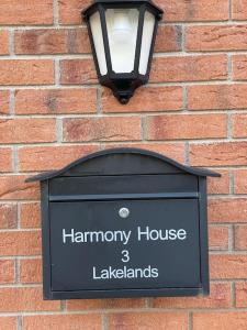 ein Schild an der Seite einer Ziegelmauer mit einer Lampe in der Unterkunft Harmony House enclosed property near beach and lake in Tramore