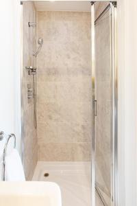La salle de bains est pourvue d'une douche avec une porte en verre. dans l'établissement The Cleveland, à Londres