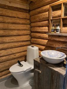 a bathroom with a toilet and a sink in a log cabin at Hesla Farm in Gol