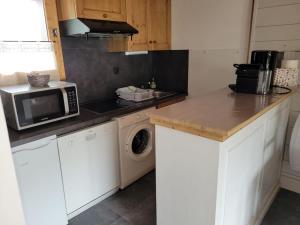 a kitchen with a microwave and a washing machine at Charmant Appartement Bozel Centre in Bozel