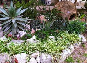 a garden with plants and rocks and a tree stump at Makis Rooms Katelios in Katelios