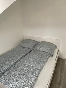 Una cama blanca con almohadas grises en un dormitorio en Wohnung im Gästehaus en Bernau bei Berlin