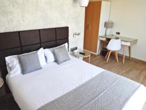 een slaapkamer met een groot wit bed en een bureau bij Hotel Lloret Ramblas in Barcelona