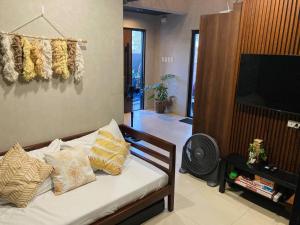 um quarto com uma cama com almofadas e uma televisão em Loft-type Pool Villa near Clark (Casa Isabela) 