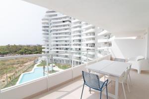 einen Balkon mit einem Tisch, Stühlen und einem Pool in der Unterkunft Global Properties, Apartamento con terraza, vistas al mar y a la piscina in Canet d'en Berenguer