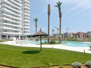 ein Resort mit einem Pool, Palmen und einem Gebäude in der Unterkunft Global Properties, Apartamento con terraza, vistas al mar y a la piscina in Canet d'en Berenguer