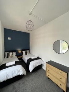 a bedroom with two beds and a mirror at Warner Brothers Apartment in Watford
