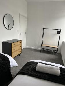 a bedroom with a bed and a mirror and a dresser at Warner Brothers Apartment in Watford
