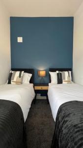 twee bedden in een kamer met een blauwe muur bij Warner Brothers Apartment in Watford