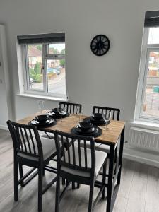a dining room table with chairs and a clock on the wall at Warner Brothers Apartment in Watford