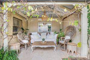 un patio con sofá, sillas y mesa en Firebird Cottage A Hallmark to Adelaides History, en Bowden