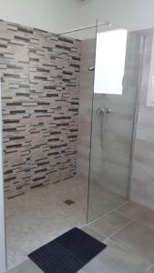 ein Badezimmer mit einer Glasdusche mit Ziegelwand in der Unterkunft Montalivet à 1km,Villa(jardin)à 1km plages wifi in Vensac