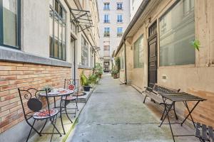 Apartment Center of Paris by Studio prestige في باريس: زقاق به طاولات وكراسي ومقعد
