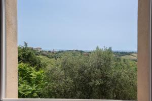 uma janela com vista para árvores e colinas em Porta Romana Elegant House with Private Parking! em Siena
