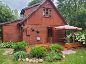 a small wooden house with a table and an umbrella at Dom pod jabłonkami in Zarzecze