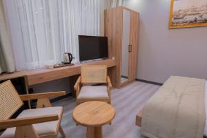 a small room with a desk with a television and a bed at Galata Greenland Hotel in Istanbul