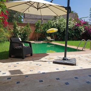 een parasol en een stoel naast een zwembad bij Villa Ama in Marrakesh
