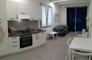 Il comprend une cuisine et un salon avec une cuisinière et une table. dans l'établissement Dépendance con giardino fronte mare, à Alghero