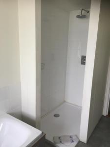 een badkamer met een douche en een wit bad bij The Corner House in Halesworth