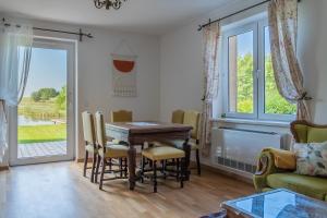 una sala da pranzo con tavolo, sedie e finestra di Siedlisko Wiłkupie, Dom nad stawem a Wiżajny