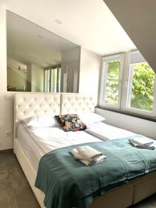 um quarto com uma grande cama branca e 2 janelas em KHAN Apartments LJUBLJANA em Ljubljana