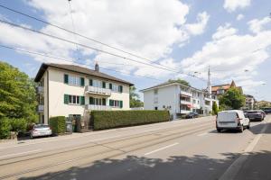 Une rue avec des voitures qui descendent dans une rue avec des bâtiments dans l'établissement STAYY Bijou Balgrist nahe Spital - gratis Parkplatz, à Zurich