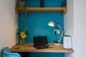 a desk with a laptop computer on a blue wall at Monk Street Apartments by Abergavenny 3-Peak Properties in Abergavenny