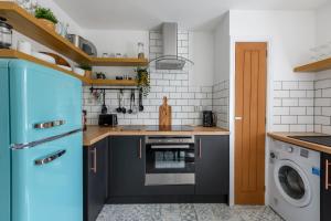 Il comprend une cuisine équipée d'un réfrigérateur bleu et d'un lave-linge. dans l'établissement Monk Street Apartments by Abergavenny 3-Peak Properties, à Abergavenny