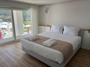 a bedroom with a large bed and a large window at Rupestre Arts Hotel Ródão in Vila Velha de Ródão