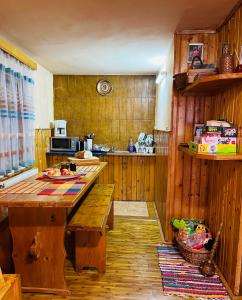 eine Küche mit Holzwänden, einem Holztisch und einer Bank in der Unterkunft Casuta noastra din Predeal in Predeal