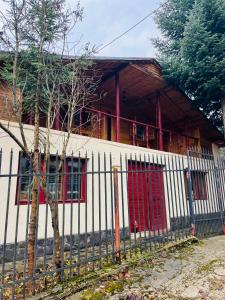 ein weißes Haus mit roten Fenstern und einem Zaun in der Unterkunft Casuta noastra din Predeal in Predeal