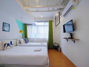 a hotel room with two beds and a tv at The Ellis Bangkok in Makkasan