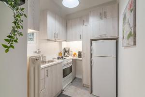 uma cozinha com armários brancos e um frigorífico em Aegle by Heloni Apartments em Atenas
