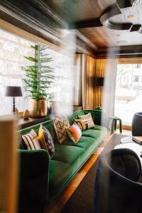 un sofá verde con almohadas en la sala de estar. en Appart Hotel Knappaboda, en Lech am Arlberg