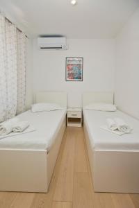 two beds in a room with white walls and wooden floors at Luka's Lodge Guesthouse & Hostel in Hvar