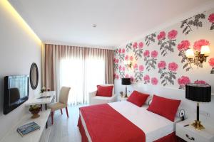 a bedroom with a red and white bed and a tv at Ladonia Hotels Mio Bianco in Akyarlar
