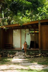 a woman sitting on the porch of a house at Grün Resort Uluwatu in Uluwatu