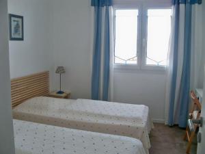 een slaapkamer met 2 bedden en 2 ramen bij RÉF 323 LARMOR PLAGE 18 rue Beg Tal Men in Larmor-Plage