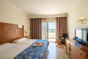 um quarto de hotel com uma cama e uma televisão de ecrã plano em Occidental Marco Polo em Hammamet