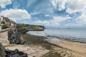 a view of a beach with houses and the ocean at Il y a de l'amour dans l'air - studio lit king size in Arromanches-les-Bains