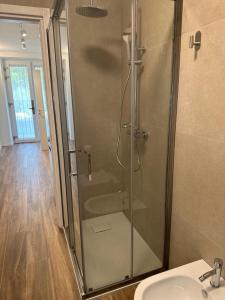 a shower with a glass door next to a sink at San Pellegrino Suites in San Pellegrino Terme