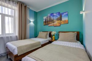 2 camas en una habitación con paredes azules en Viva Hotel, en Bishkek